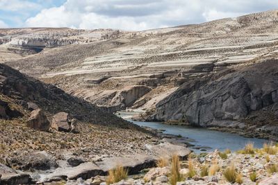 Scenic view of river by mountains against sky