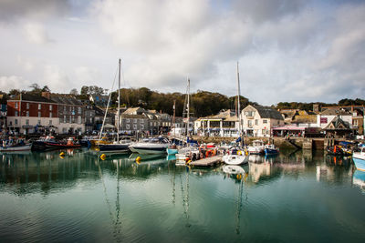 Boats moored at harbor against sky