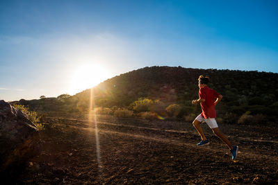 Full length of teenage boy running on mountain against sky