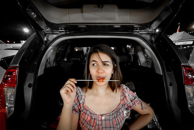 Portrait of young woman eating car