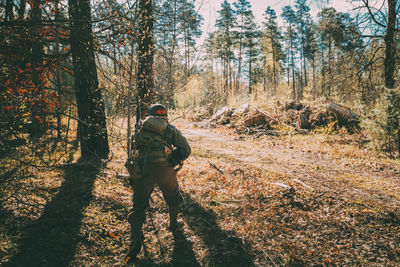 Rear view of man standing amidst trees in forest