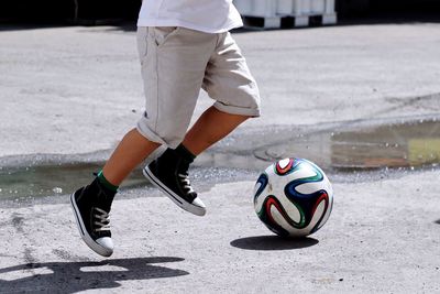 Low section of person playing soccer on sunny day