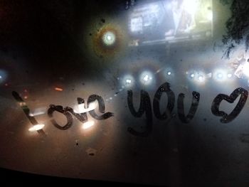 Close-up of text on wet glass window