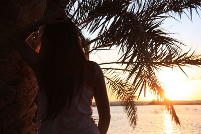 Rear view of woman at beach against sky