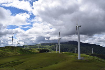 Windmills on field against sky