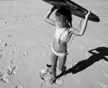 High angle view of girl carrying surfboard on head at beach