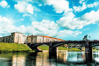 Arch bridge over river against sky in city