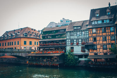 Buildings by river against sky in city