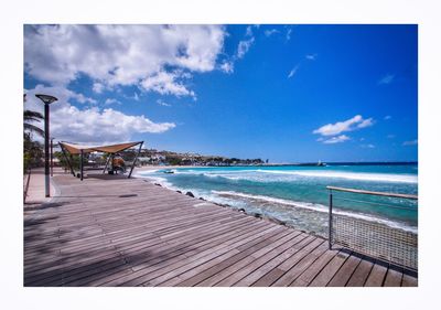 Empty chairs on beach against blue sky