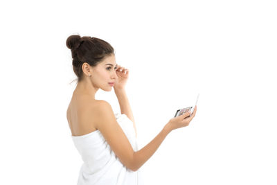 Young woman holding beauty product against white background