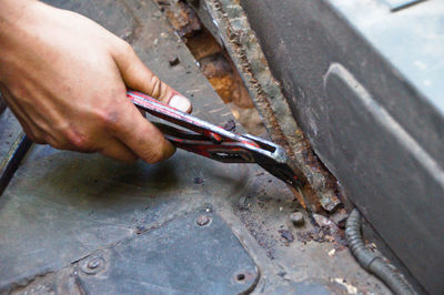 Close-up of hand cutting metal with pliers