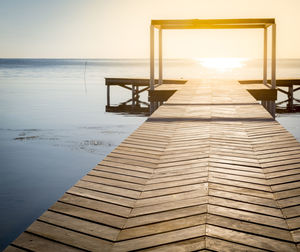 Pier over sea against sky during sunset