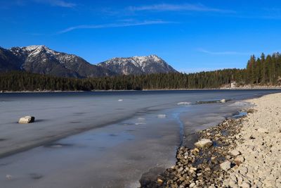 Scenic view of lake and mountains against blue sky