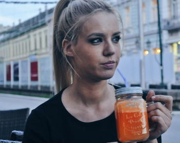 Close-up of young woman with drink in city