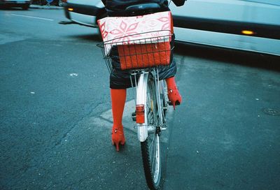 Low section of woman riding bicycle on road