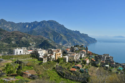 High angle view of townscape by sea against clear blue sky