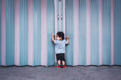 Full length of girl standing against multi colored door