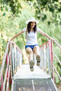 Full length of woman jumping on footbridge