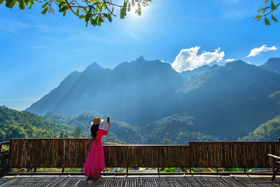 Rear view of woman standing on mountain against sky