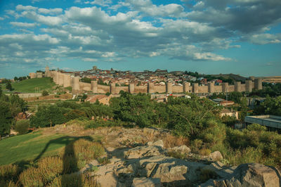 Stone towers with large wall over the hill, encircling the avila houses at sunset, in spain.