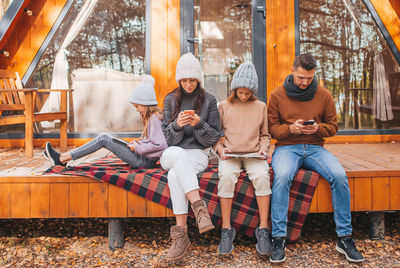 Full length of young couple sitting on outdoors