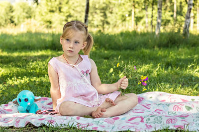 Cute girl holding flowers sitting at park
