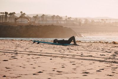 Man on beach in city against clear sky