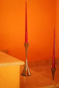 Close-up of red candle  against orange wall