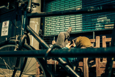 Person using phone while lying on bench in city