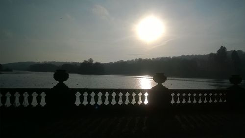 Silhouette swans on sea against sky during sunset
