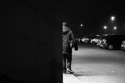 Man standing in front of illuminated building at night