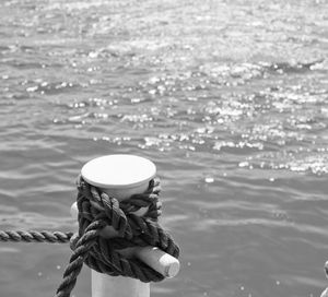 Close-up of rope tied on post against sea