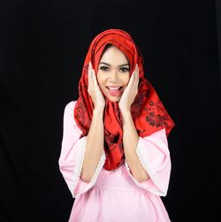Portrait of smiling young woman against black background