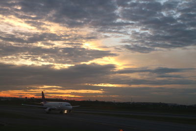 Cars on airplane against sky during sunset