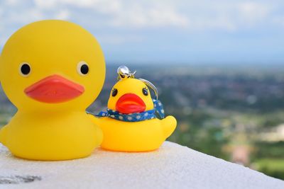 Close-up of rubber ducks on retaining wall against sky