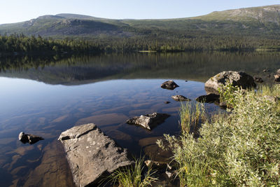 Scenic view of lake with rocky shore against mountain