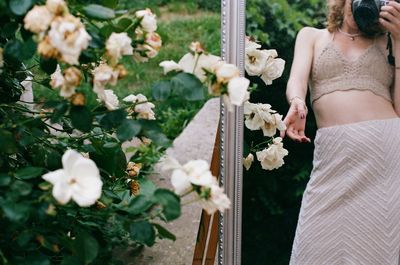 Midsection of woman standing by white flowers