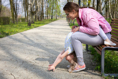 The daughter tilts her head completely down and the mother belays the little gymnast.