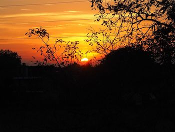 Silhouette trees on landscape against romantic sky at sunset