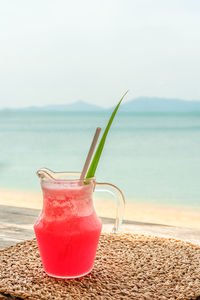 Close-up of drink on beach against sky