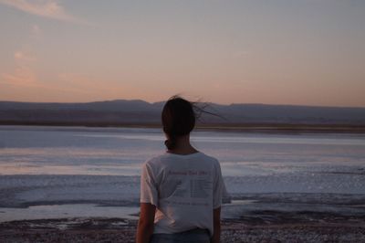 Rear view of man looking at sea against sky