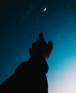 Low angle view of silhouette hand against blue sky