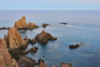 Rocks in sea against clear sky