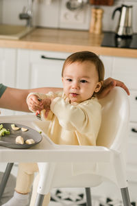 Portrait of cute baby boy holding food at home