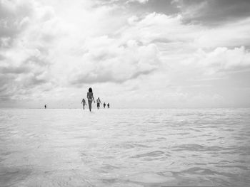 People at beach in isla holbox against cloudy sky