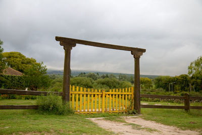 Fence on field against cloudy sky