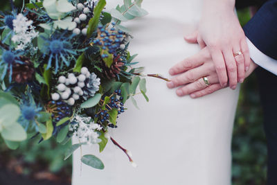 Midsection of bride holding groom hand during wedding ceremony