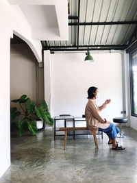 Side view of woman sitting on chair at home