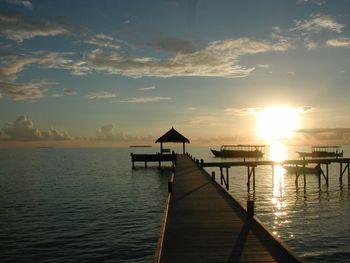 Pier over sea against sky during sunset