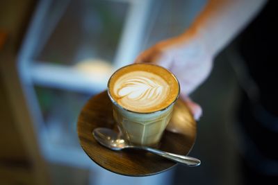 Cropped hand holding cappuccino cup